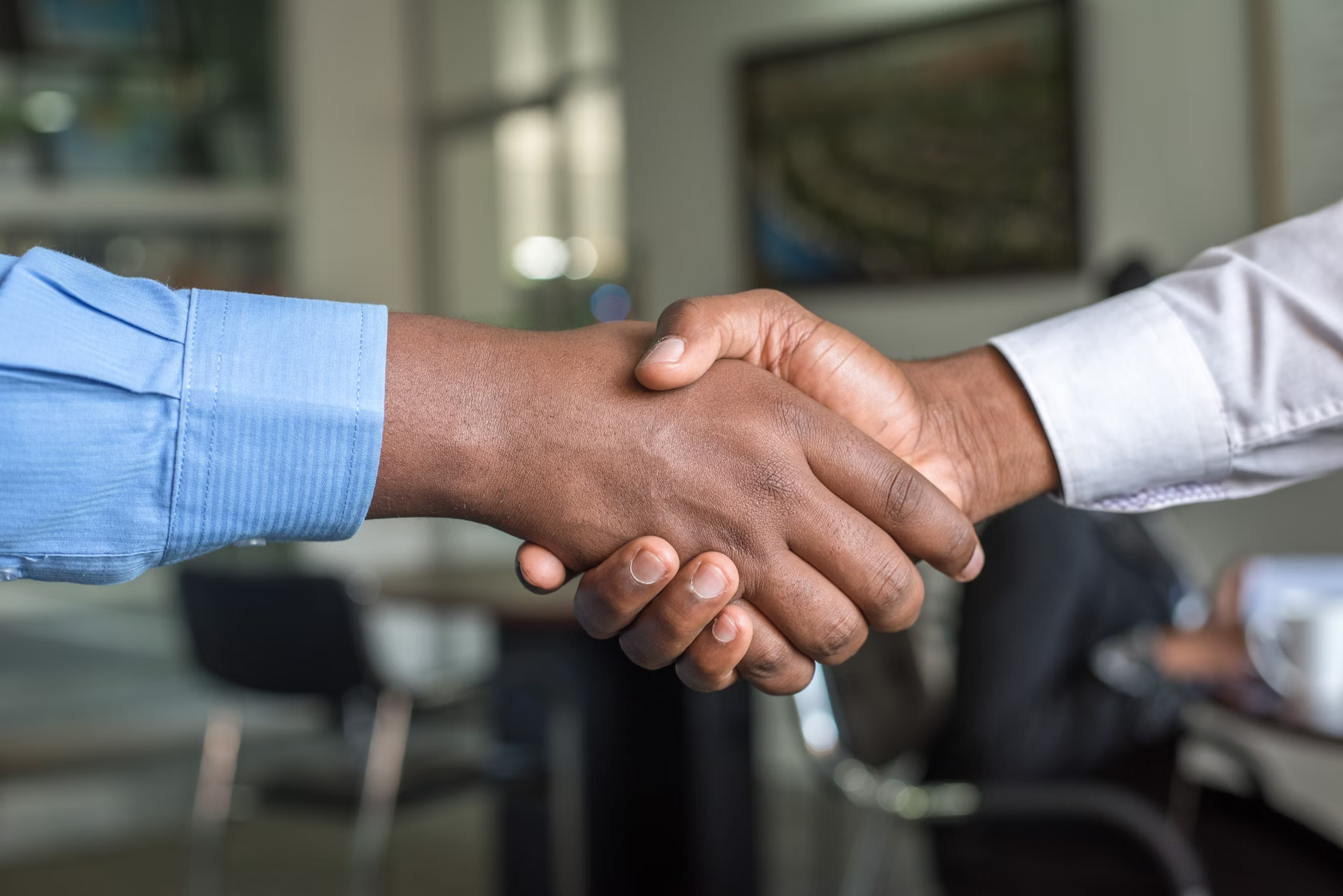 Two business professionals shaking hands in an office, symbolizing trusted deals and readiness.